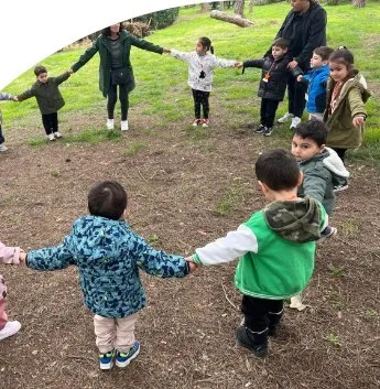 Bahçede el ele halka olmuş çocuklar
