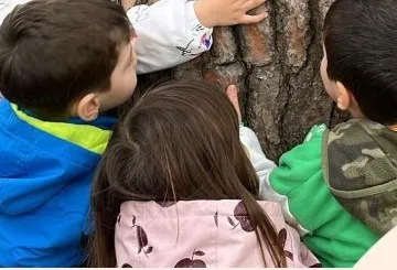 Bahçede ağacı inceleyen çocuklar
